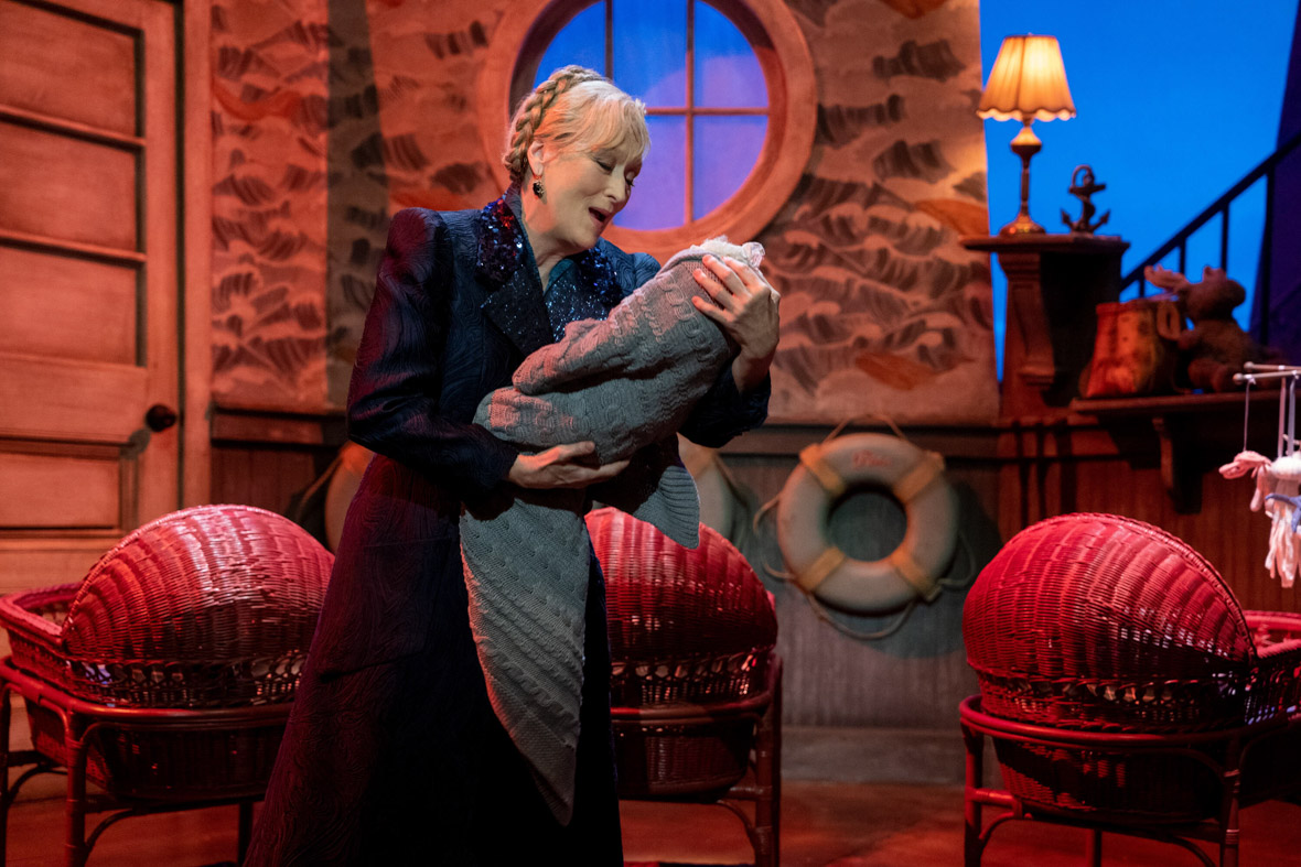 Loretta, played by Meryl Streep, performs onstage in Only Murders in the Building. She is holding a swaddled baby and is surrounded by several wicker bassinets.